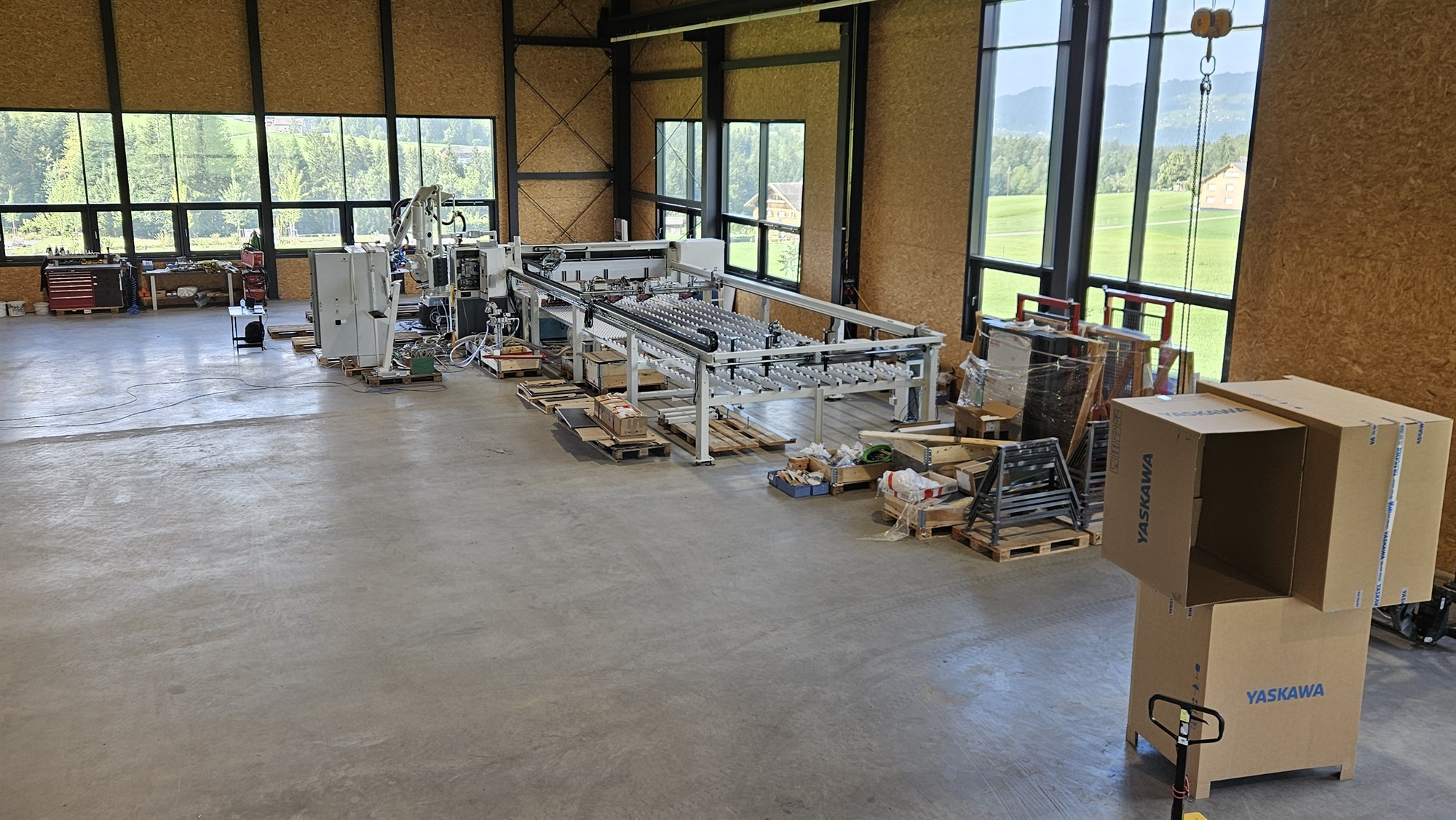 Automatisierte Produktionsanlage mit Fördertechnik und Roboter in der Werkshalle