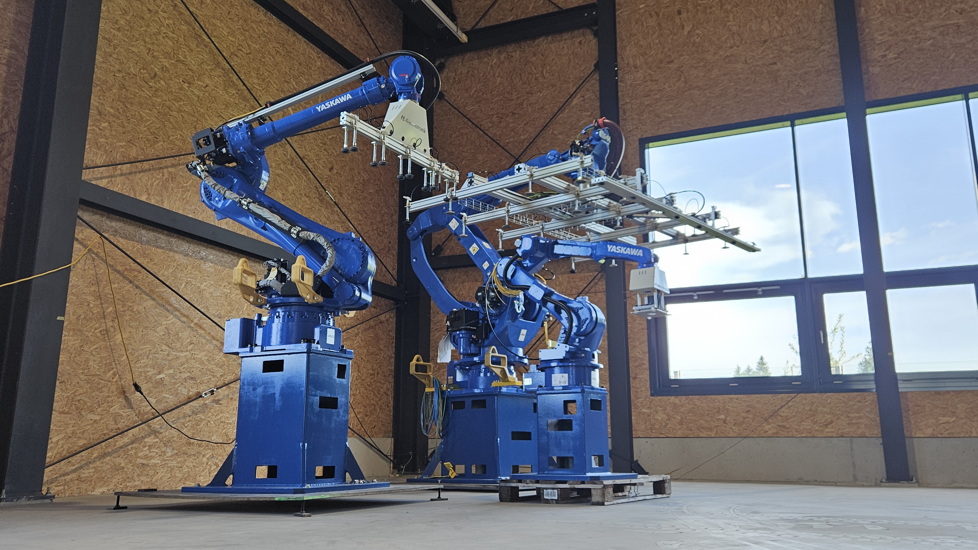 Zwei Yaskawa-Industrieroboter mit kundenspezifischen Greifersystemen